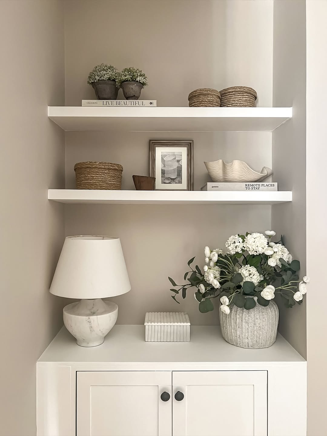 Neutral shelves styled with baskets, books, and a vase of flowers create a cozy yet uncluttered look.