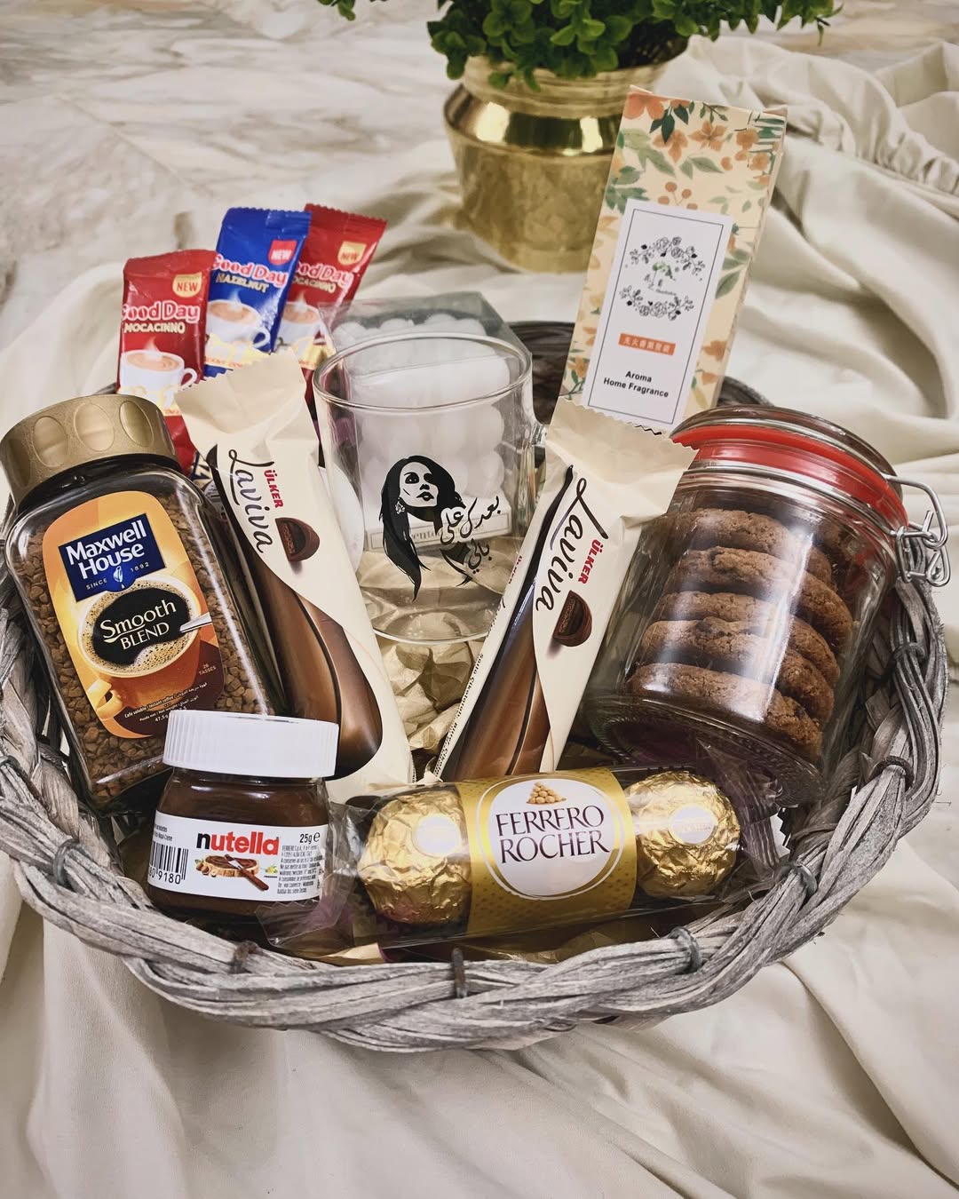 A beautifully arranged basket filled with coffee, chocolates, cookies, Nutella, and a scented item for a cozy touch.