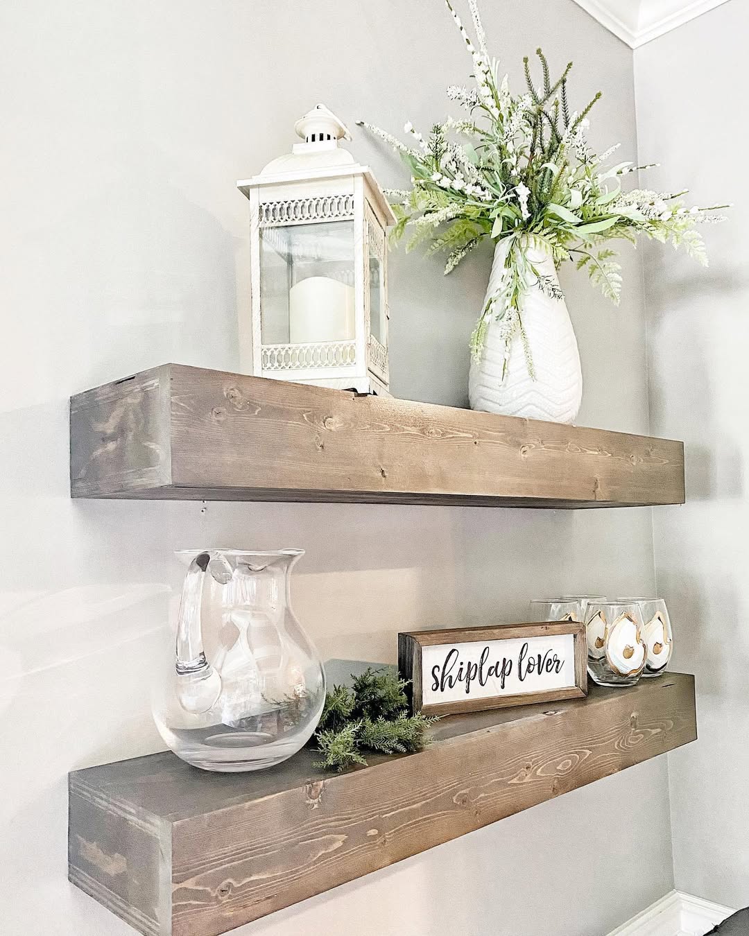 Floating shelves with lanterns, flowers, and a “shiplap lover” sign highlight personal style.
